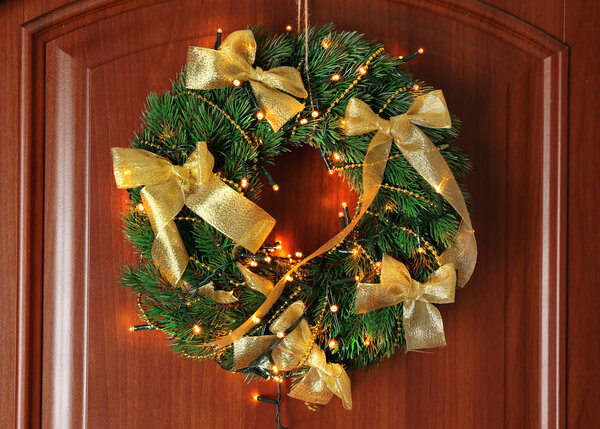 Красивый рождественский венок с гирляндой на двери
