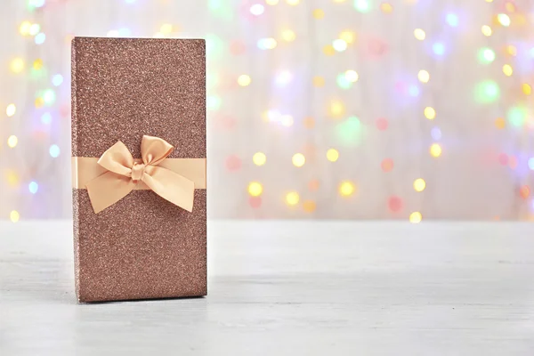 Caixa com presente de Natal na superfície de madeira contra luzes desfocadas — Fotografia de Stock