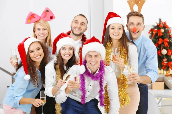 Young people with glasses of champagne celebrating Christmas at corporate party in office