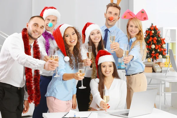 Young people with glasses of champagne celebrating Christmas at corporate party in office