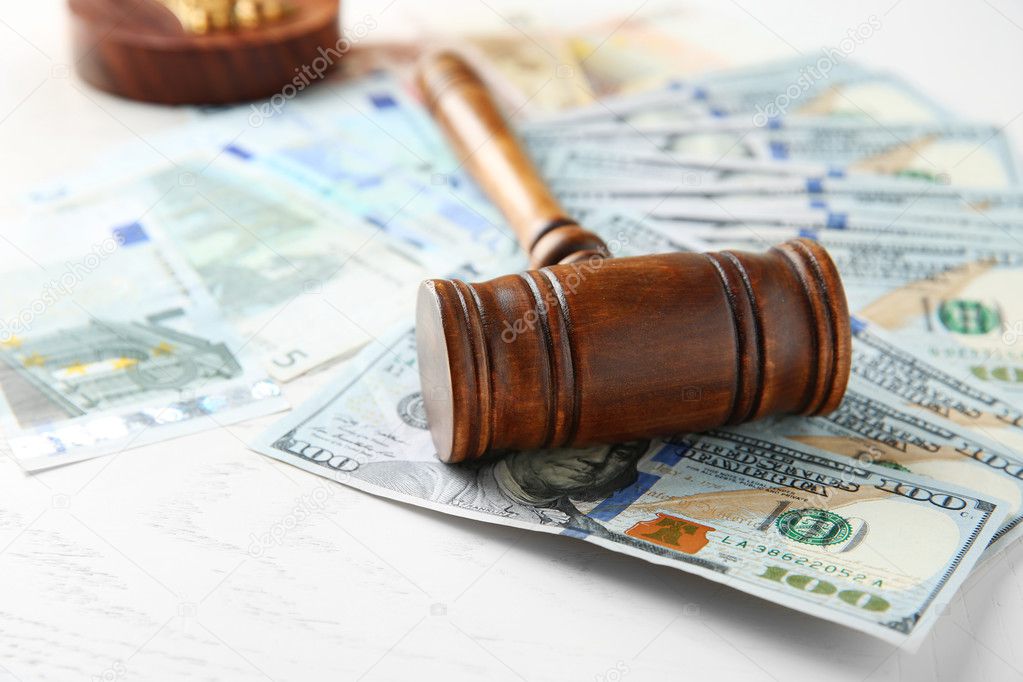 Judge's gavel and dollar banknotes on white table