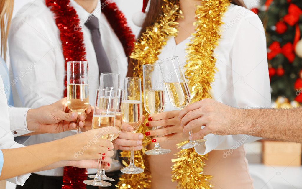 Young people with glasses of champagne celebrating Christmas at corporate party, close up view