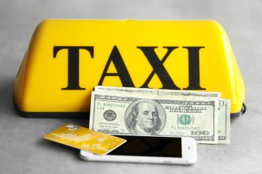 Sarı taksi çatı işareti ile telefon, kredi kartı ve gri arka plan, closeup üzerinde Amerikan Doları
