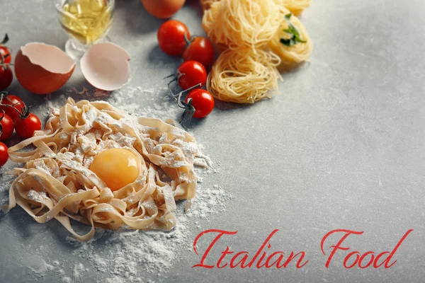 Homemade pasta with yolk on table. Text ITALIAN FOOD on gray background. Traditional meal concept. — Stock Photo, Image