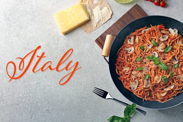 Pan met heerlijke pasta op houten snijplank. Word Italië op grijze achtergrond. Italiaans eten concept. — Stockfoto