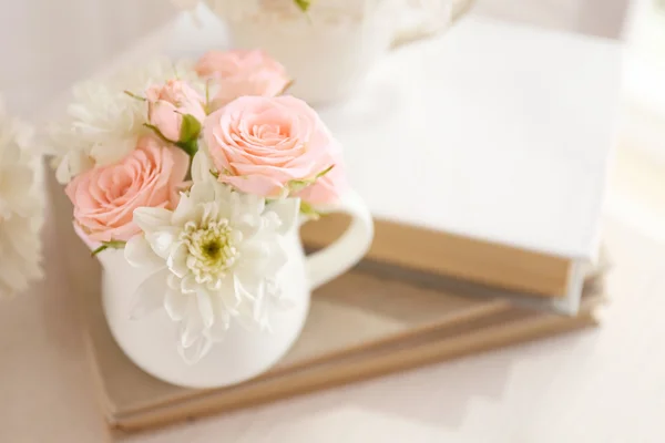 Bouquet af smukke roser i en kop på en bog - Stock-foto