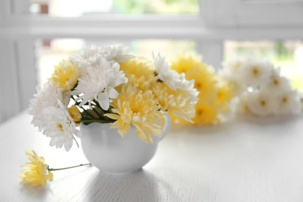 Boeket van mooie bloemen in een kopje op een tafel — Stockfoto