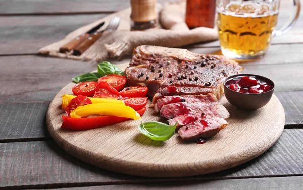 Grilovaný steak s čerstvou zeleninou, omáčkou a pivem na dřevěný stůl — Stock fotografie