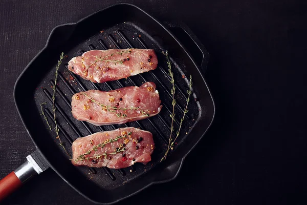 Steaks crus aux herbes et épices sur une poêle à griller — Photo