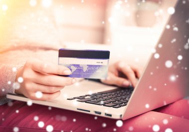 Kredi kartı ve dizüstü bilgisayar, closeup ile eller. Karlı etkisi, online Noel kavramı alışveriş.