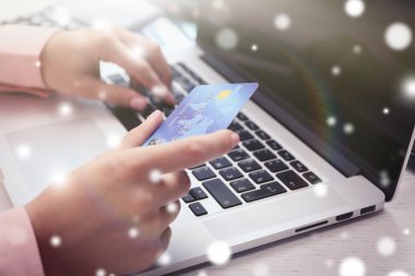 Kredi kartı ve dizüstü bilgisayar, closeup ile eller. Karlı etkisi, online Noel kavramı alışveriş.