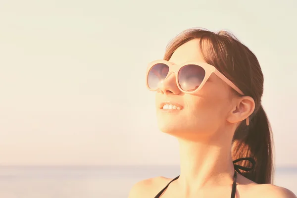 Młoda kobieta w okularach słonecznych na plaży — Zdjęcie stockowe