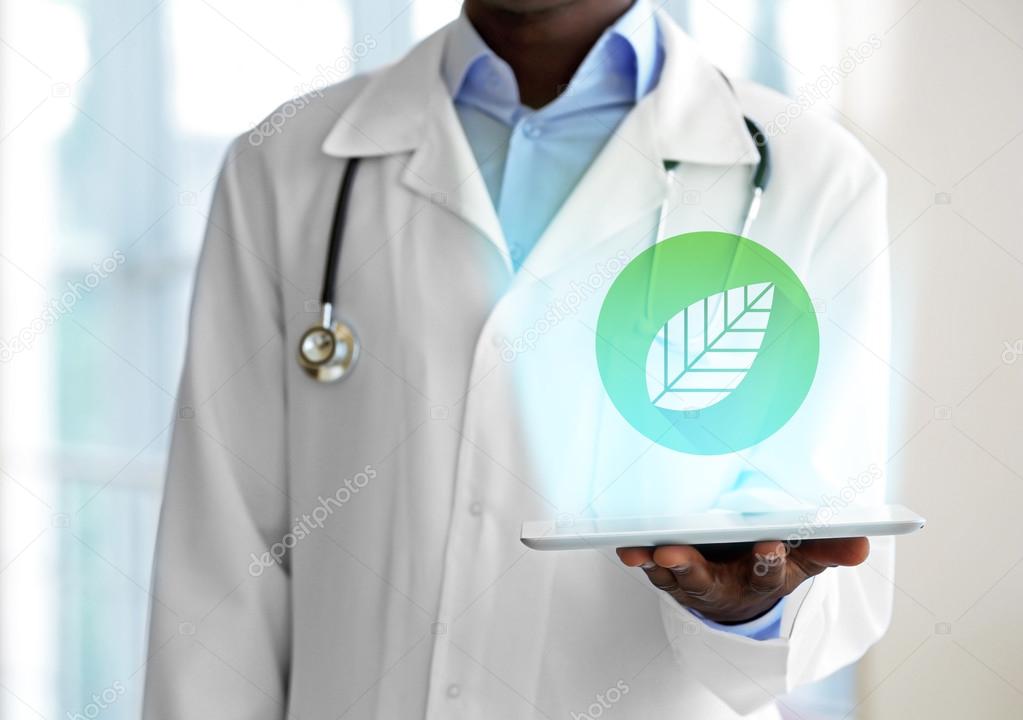 Doctor hand holding tablet with projection of leaf. Alternative medicine concept.