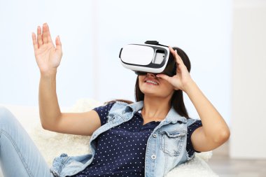 Divan bir odada sanal gerçeklik gözlüklü genç kadın