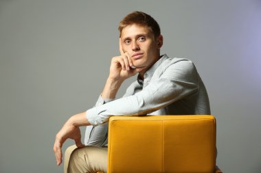 Renkli arka plan üzerinde sandalye üzerinde oturan genç adam