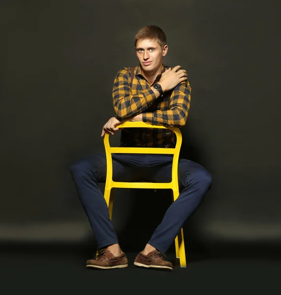 Uomo elegante seduto sulla sedia su sfondo scuro — Foto Stock