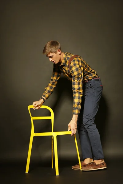 Uomo elegante con sedia su sfondo scuro — Foto Stock