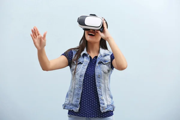 Молодая женщина в очках виртуальной реальности на светлом фоне — стоковое фото