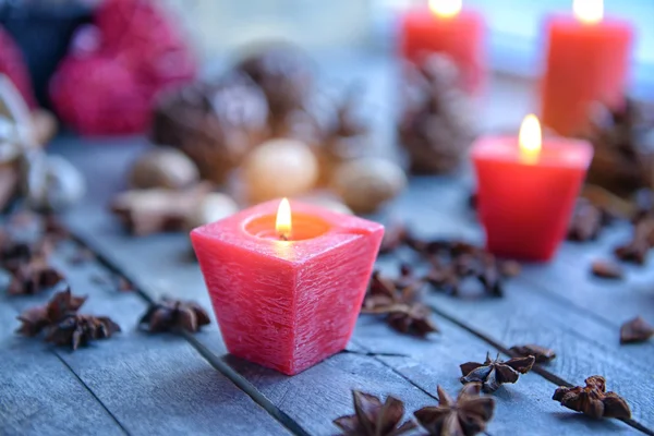 Red candle and anise stars on wooden background, close up view — Stock Photo, Image