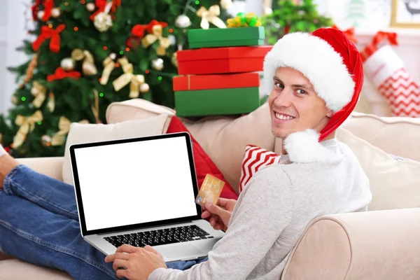 Ung man handla online med kreditkort hemma till jul — Stockfoto