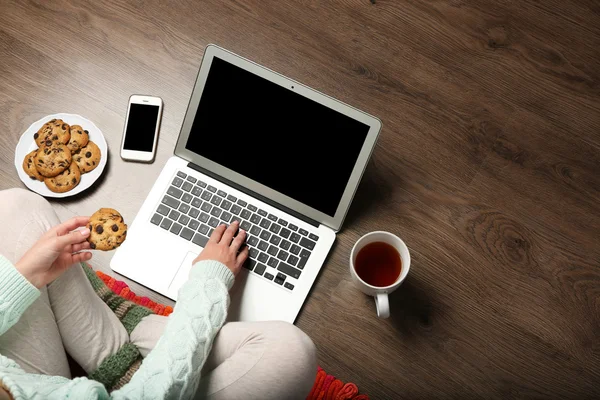 Дівчина з ноутбуком і їжею розслабляється на підлозі — стокове фото