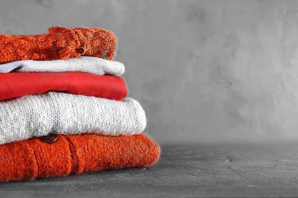 Setumpuk pakaian musim dingin yang hangat di latar belakang abu-abu — Stok Foto