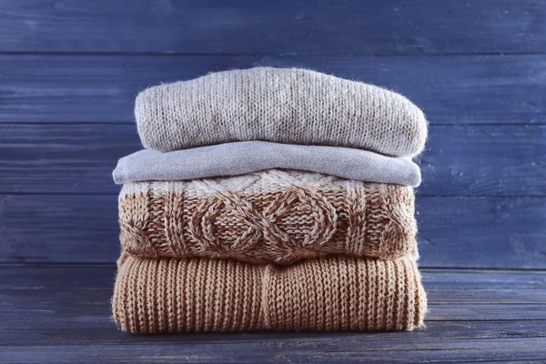 Stack of warm winter clothes on blue wooden background — Stock Photo, Image
