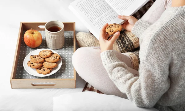 Meisje met voedsel lezen boek op bed — Stockfoto