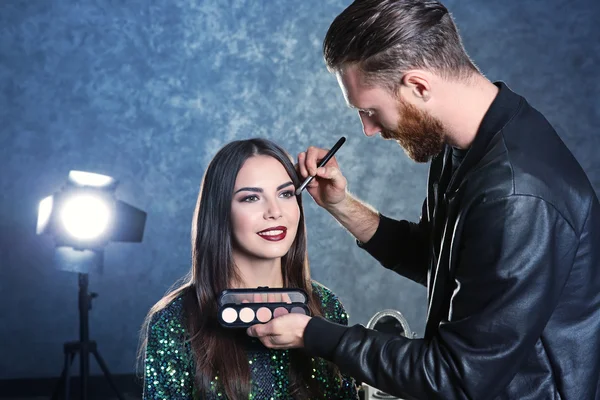 Artista de maquillaje profesional trabajando con una hermosa mujer joven — Foto de Stock