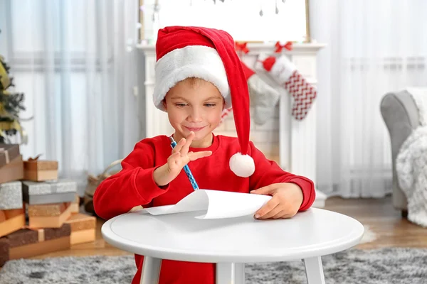 Bonito menino escrevendo carta para Papai Noel na mesa — Fotografia de Stock