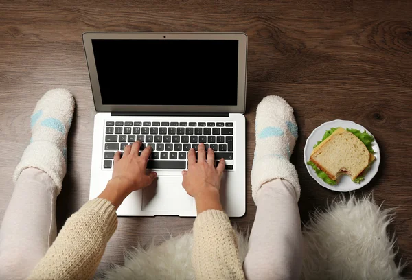 Chica con ordenador portátil y comida relajante en el suelo — Foto de Stock