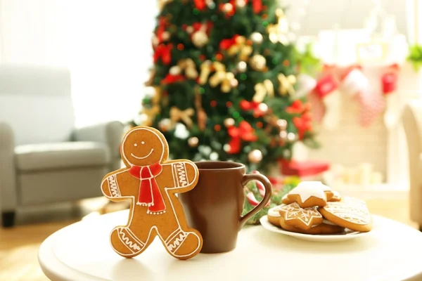 Gingerbread man, cup and plate with cookies on table against blurred background — Stock Photo, Image