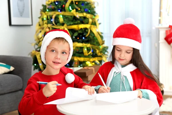 Симпатичні маленькі діти писати лист до Санта-Клауса на стіл — стокове фото