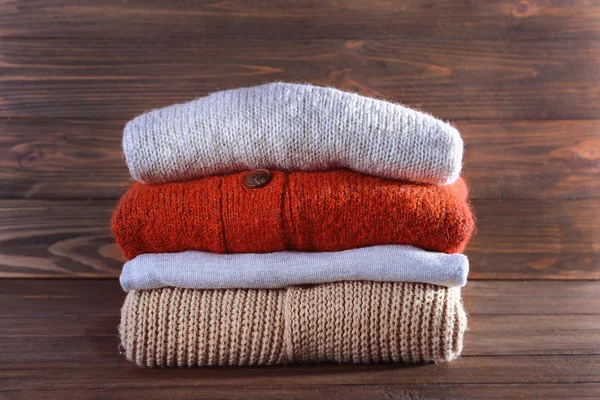 Pilha de roupas quentes de inverno no fundo de madeira — Fotografia de Stock