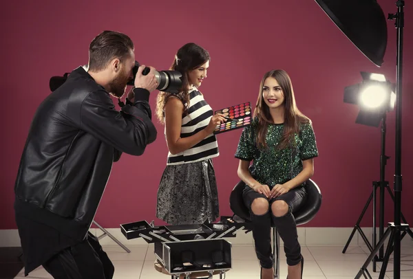 Professional makeup artist working with young beautiful woman at photo shooting — Stock Photo, Image