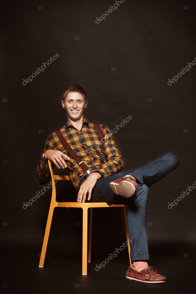 Homme élégant assis sur une chaise sur fond sombre image libre de droit