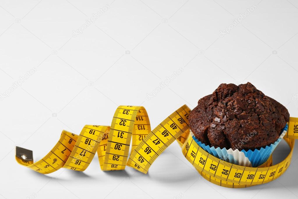 Chocolate muffin with centimeter on white background