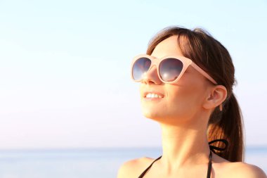 Genç kadın deniz arka plan üzerinde güneşlenme