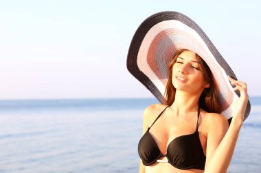 Şapka deniz arka plan üzerinde güneşlenme içinde genç kadın