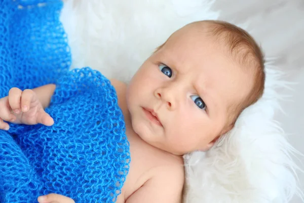 Cute baby lying on white fluffy plaid and covered with blue blanket, close up view — Stock Photo, Image