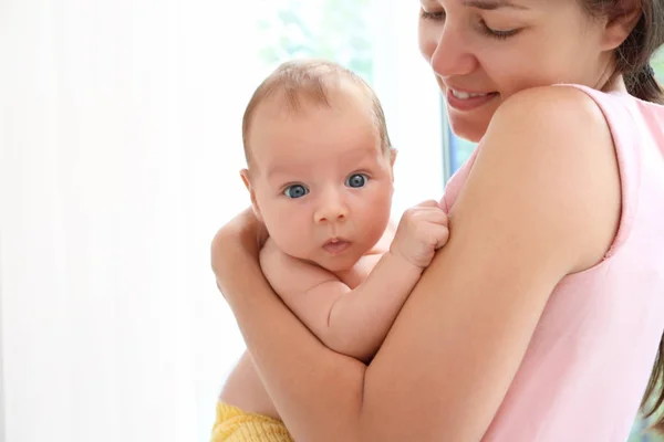 Frau mit niedlichem Baby auf hellem Hintergrund, Nahaufnahme — Stockfoto