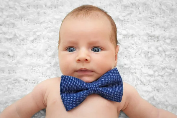 Bebê bonito com gravata borboleta deitado na colcha branca — Fotografia de Stock