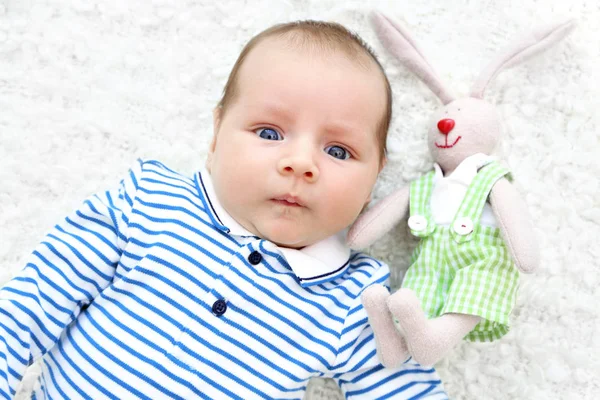 Bebê bonito com coelho fofinho deitado na colcha branca, vista de perto — Fotografia de Stock