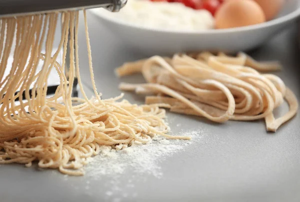 Making tagliatelle with pasta machine on kitchen table — Stock Photo, Image