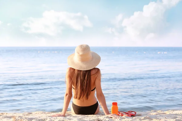 Fiatal nő a kalap napozó a tenger a háttérben — Stock Fotó