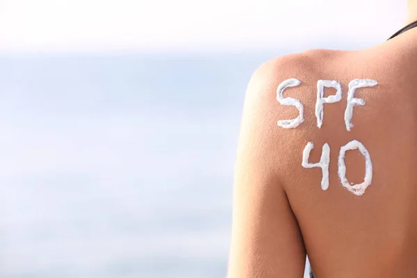 Young woman with sunscreen on back,  sea background — Stock Photo, Image