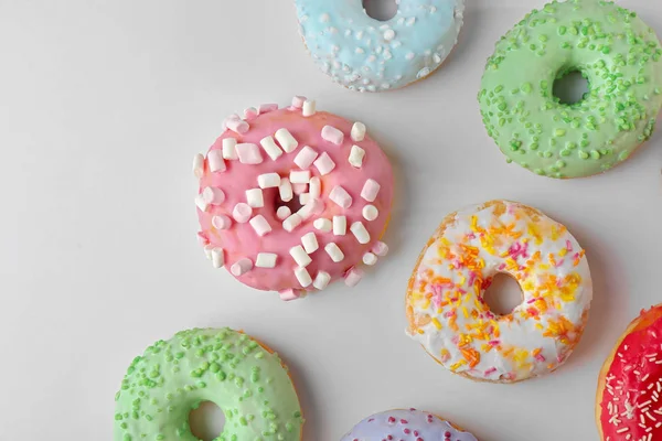 Donuts savoureux avec des aspersions colorées sur fond clair — Photo