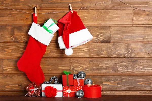 Medias de Navidad, sombrero de Papá Noel y regalos sobre fondo de madera —  Fotos de Stock