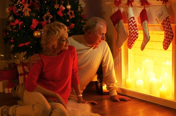 老夫婦の暖炉のそばに座っては クリスマスの装飾 — ストック写真