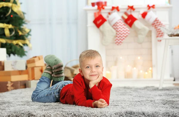 Carino ragazzo sdraiato su tappeto in soggiorno decorato per Natale — Foto Stock